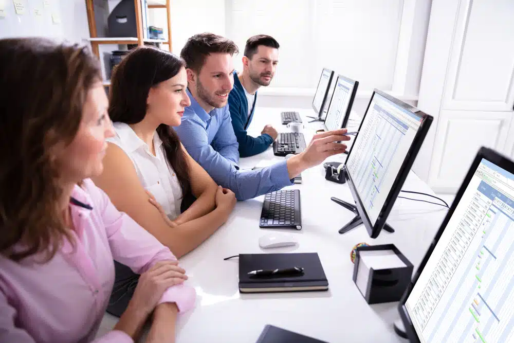 Business team reviewing data analytics on computer screens