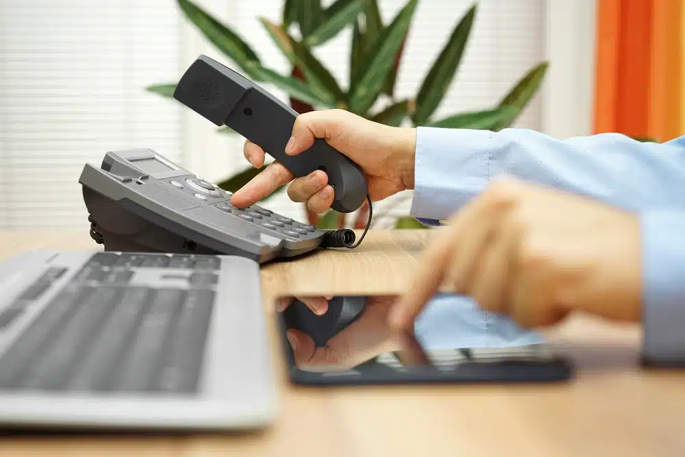 A person making a phone call, holding the device to their ear with a focused expression.