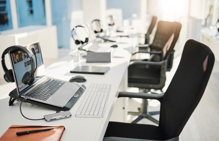 A white desk featuring a laptop and a keyboard, arranged neatly for a workspace setup.