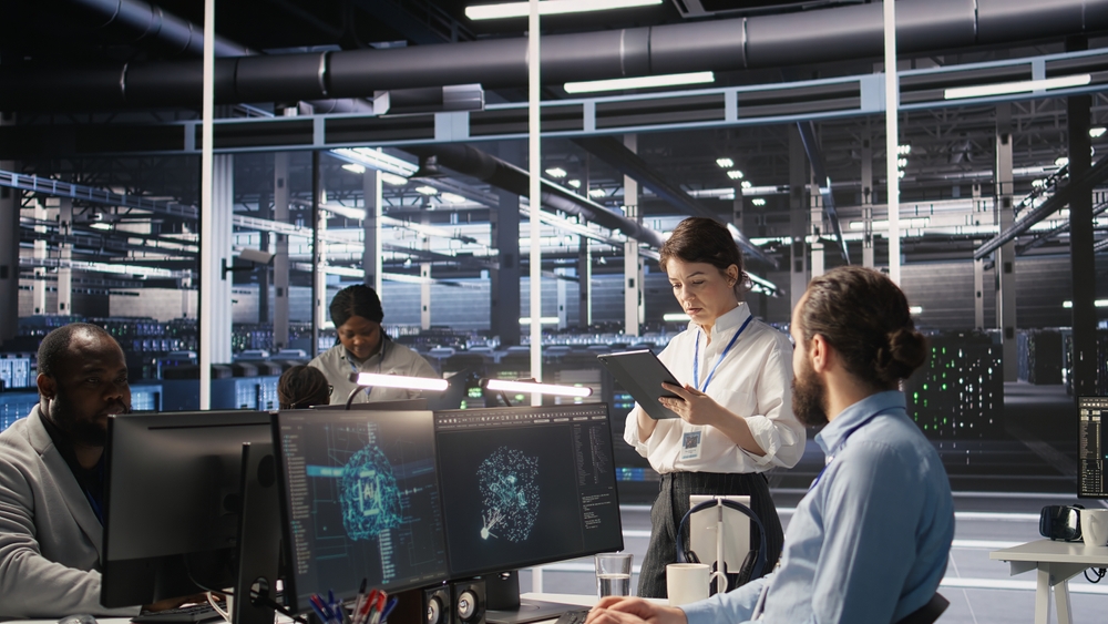 A group of people collaborating on computers in a spacious room for Xima vs Nextiva Support Operations.