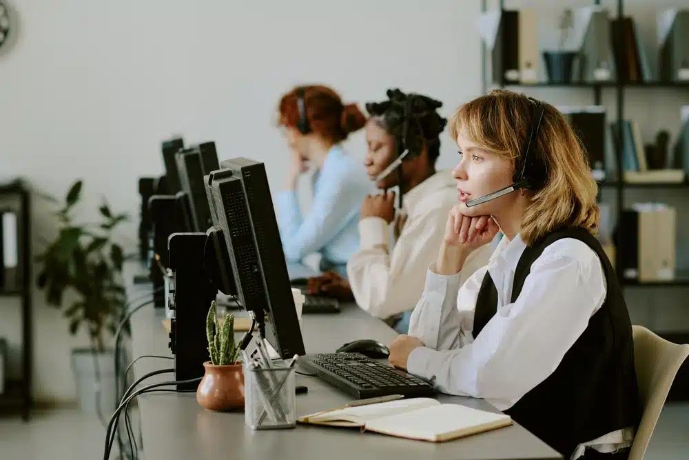 A woman wearing a headset, focused on her work in a modern office environment.