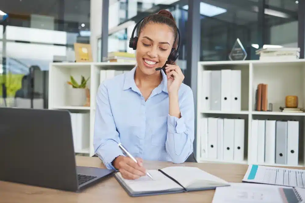 A woman with headphones sits at a desk, focused on her laptop, engaged in work or study.