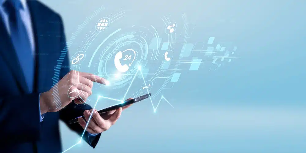 A business professional using a smartphone with a futuristic digital healthcare interface displaying communication, support, and medical technology icons on screen.