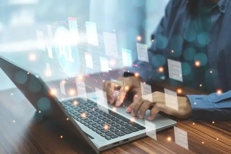 A man focused on a laptop, interacting with a digital interface displayed on the screen.