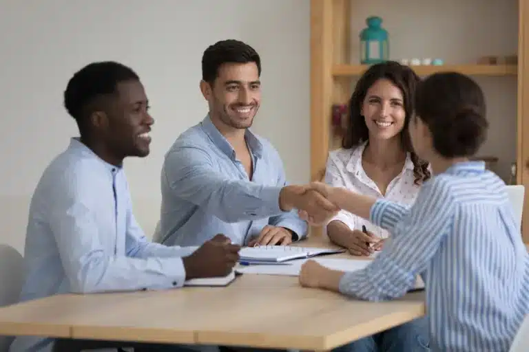 A group of diverse individuals shaking hands during a business meeting, symbolizing collaboration and agreement.
